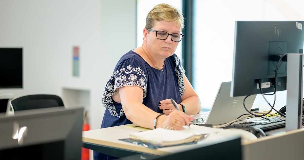 A person working at a desk with a laptop and notepad