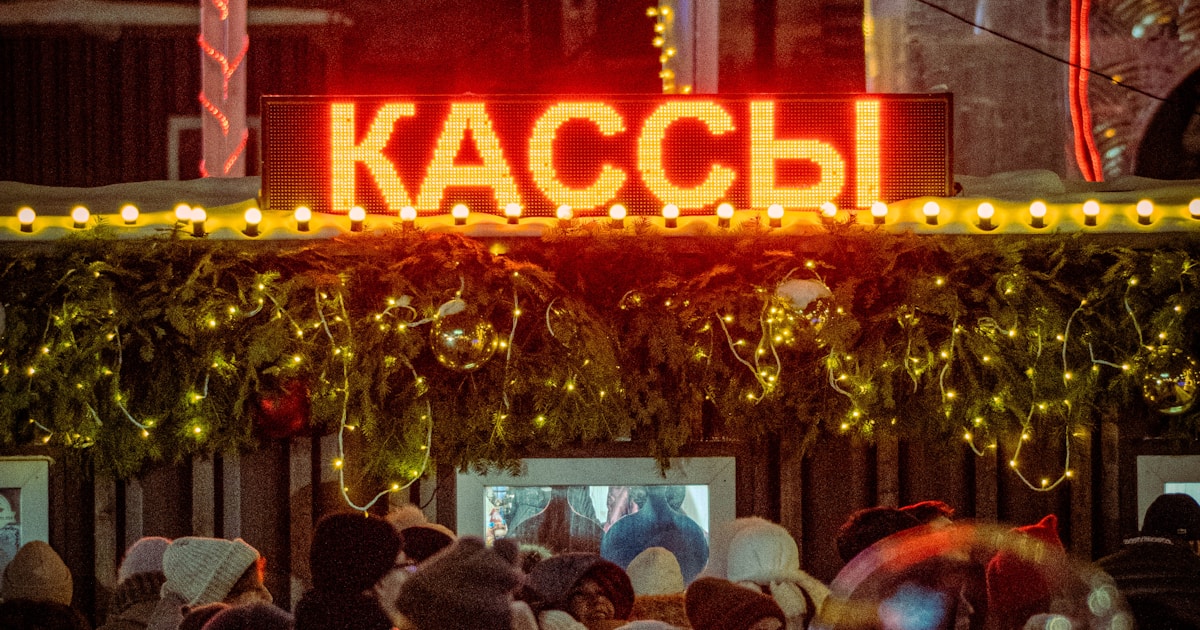People queuing at a brightly lit ticket booth at night