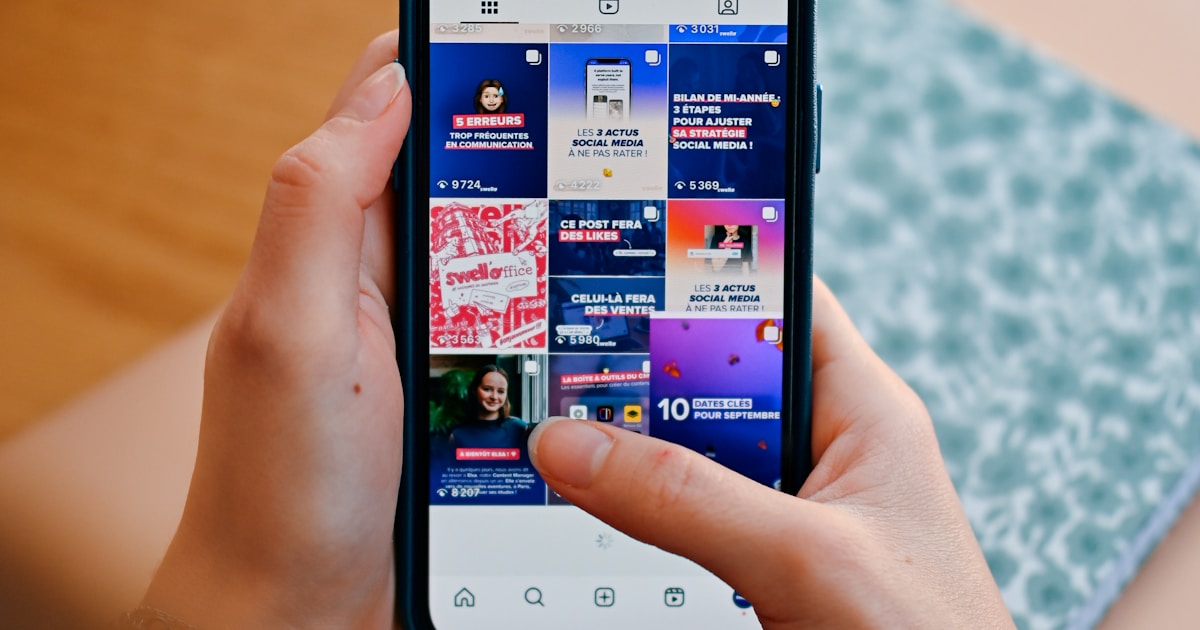 Hands holding a phone showing a social feed