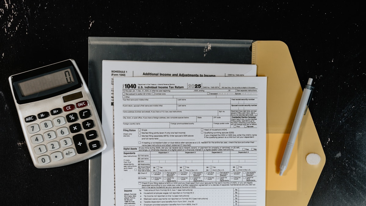 A calculator and tax forms on a dark surface